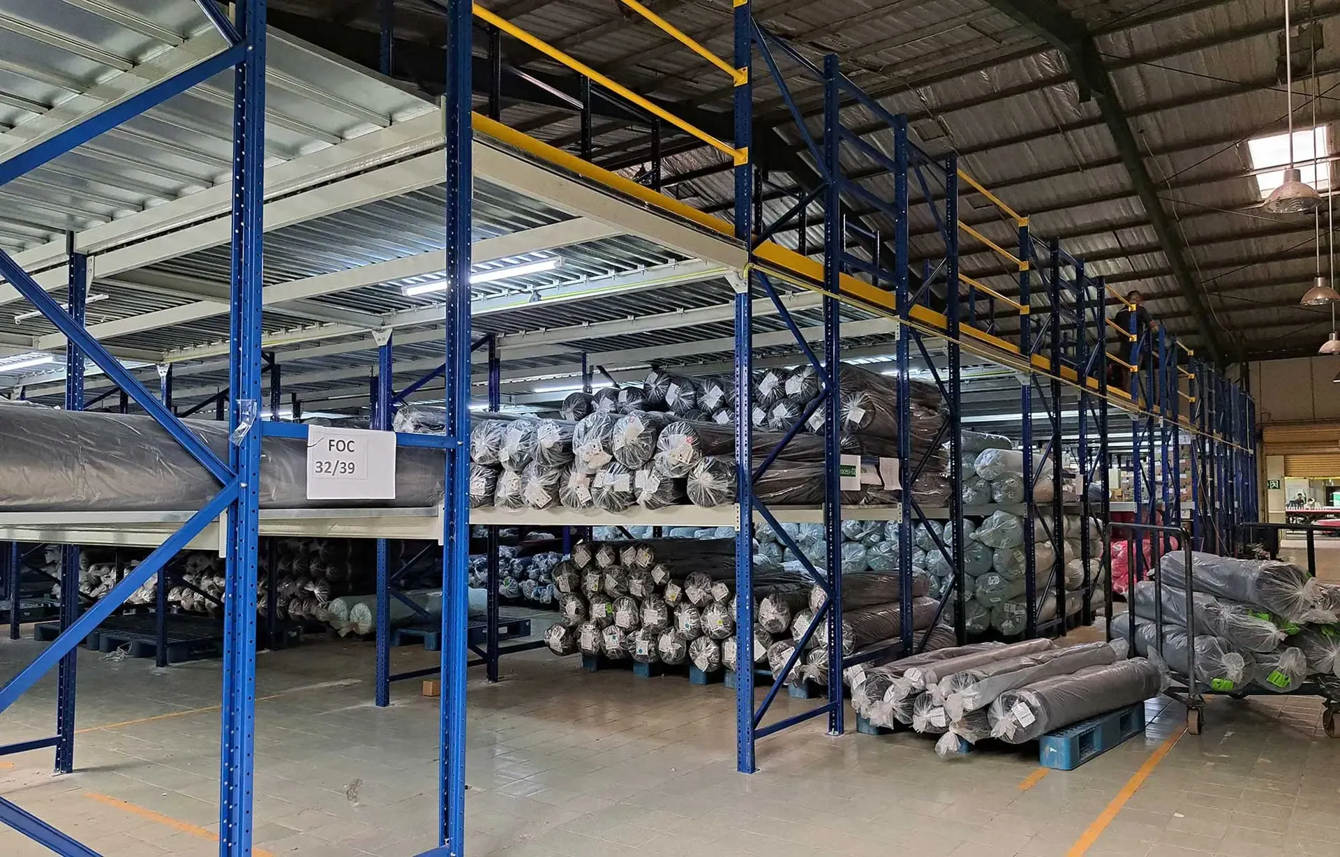 Two-tier shelving system storing fabric rolls for an apparel exporter